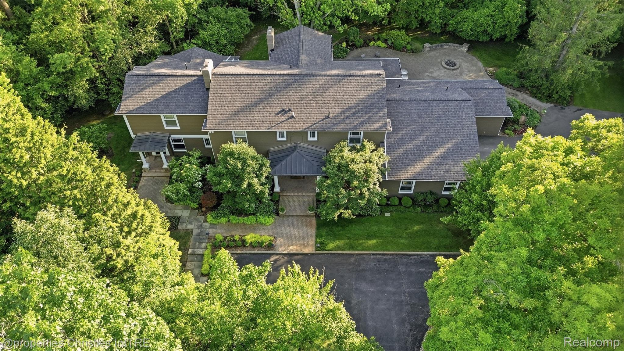25235 Canterbury Road Franklin, MI 48025 - Photo 2 of 56 Expansive property featuring a multi-level architectural style, a large paved driveway, extensive mature landscaping, a stone patio, and a dedicated fire pit area