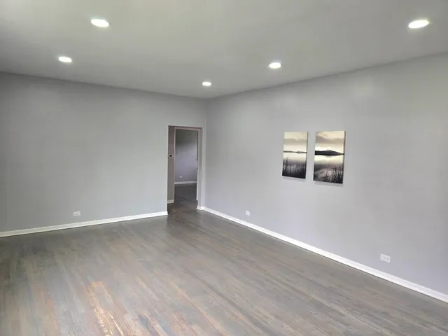 a view of an empty room with wooden floor and windows