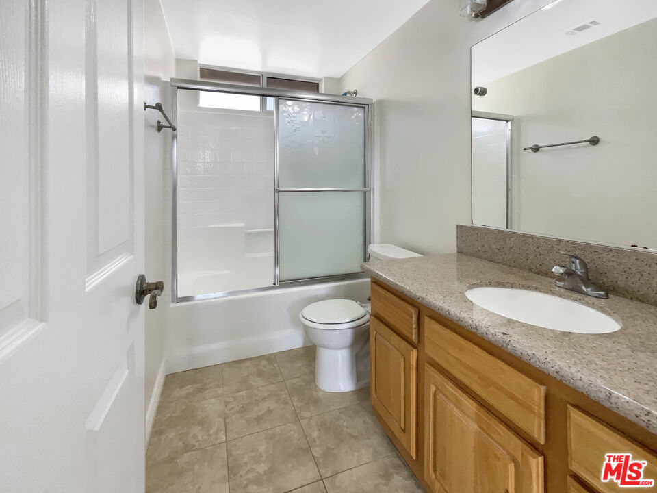 15232 Foothill Boulevard, Unit 111 Sylmar, CA 91342 - Photo 5 of 19 a bathroom with a granite countertop sink toilet a mirror and shower