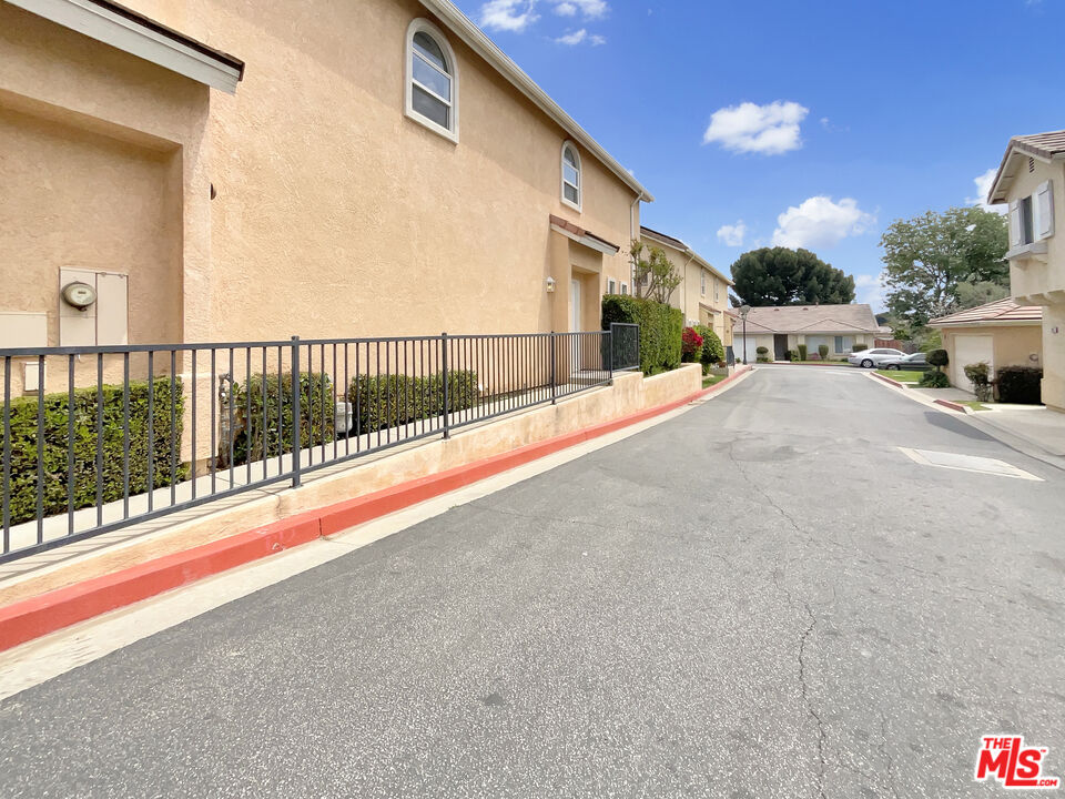 15232 Foothill Boulevard, Unit 111 Sylmar, CA 91342 - Photo 7 of 19 a view of a street with a small yard and wooden fence