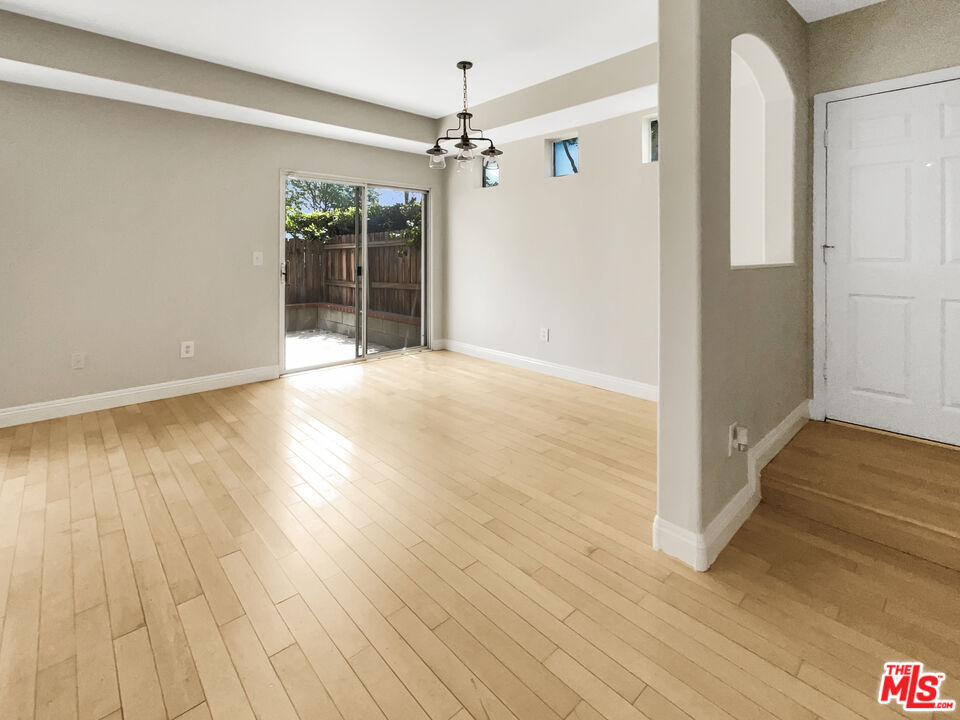 15232 Foothill Boulevard, Unit 111 Sylmar, CA 91342 - Photo 8 of 19 a view of an empty room with wooden floor and a window