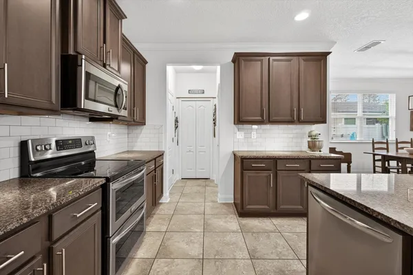 a kitchen with stainless steel appliances granite countertop a stove sink and cabinets