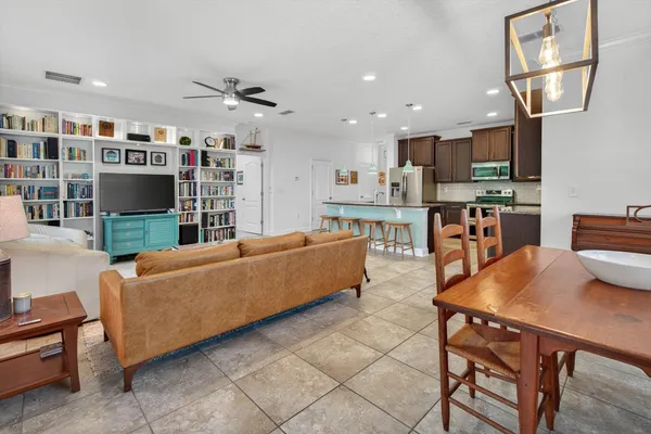 a living room with furniture kitchen view and a large window