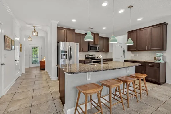 a kitchen with stainless steel appliances kitchen island granite countertop a refrigerator and a stove top oven