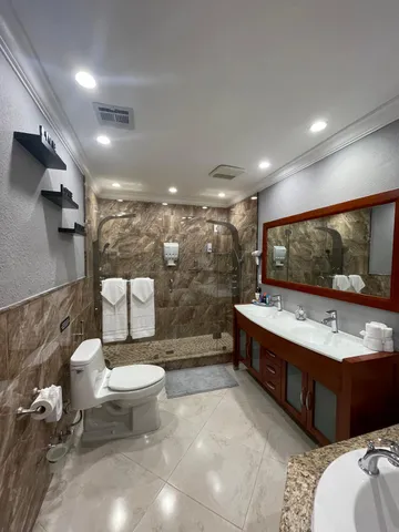 a bathroom with a double vanity sink toilet and shower