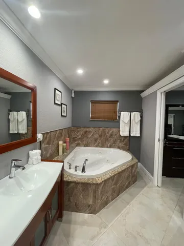a spacious bathroom with a tub sink and mirror