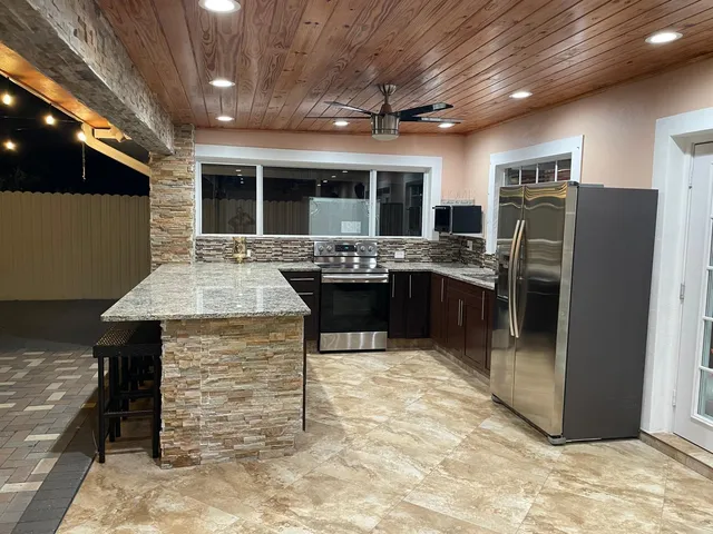 a kitchen with stainless steel appliances granite countertop a sink and a refrigerator