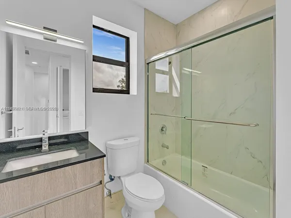 a bathroom with a granite countertop sink toilet and shower