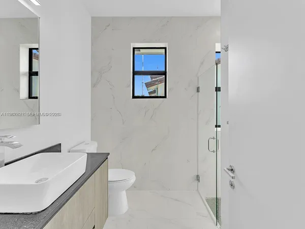 a bathroom with a granite countertop sink a toilet and mirror
