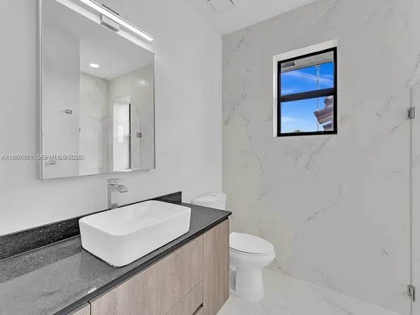 a bathroom with a granite countertop sink and a toilet