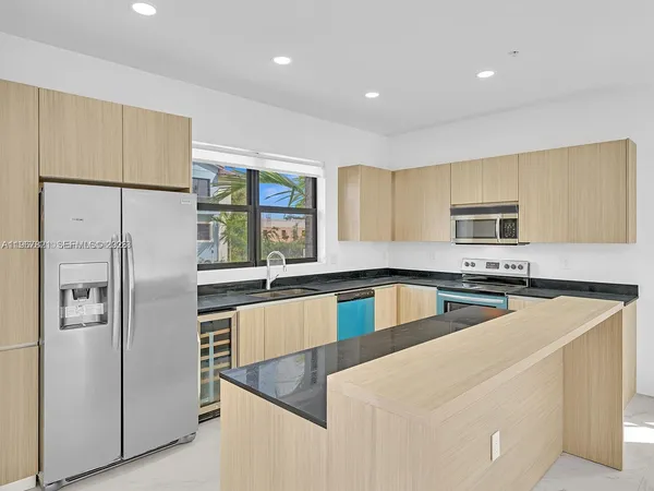 a kitchen with stainless steel appliances granite countertop a refrigerator a stove and a sink with wooden floor