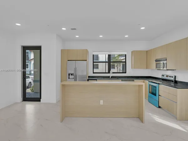 a kitchen with kitchen island a sink a stove and a refrigerator