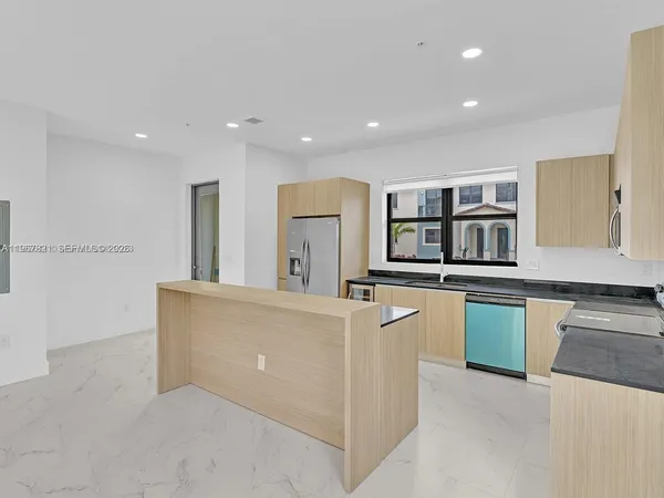 a living room with stainless steel appliances kitchen island granite countertop a refrigerator and a stove top oven