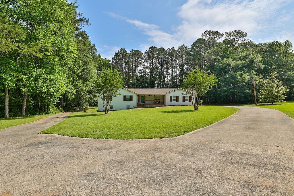 399 Rivertown Road Fairburn, GA 30213 - Photo 1 of 1 a view of a house with a big yard and large trees