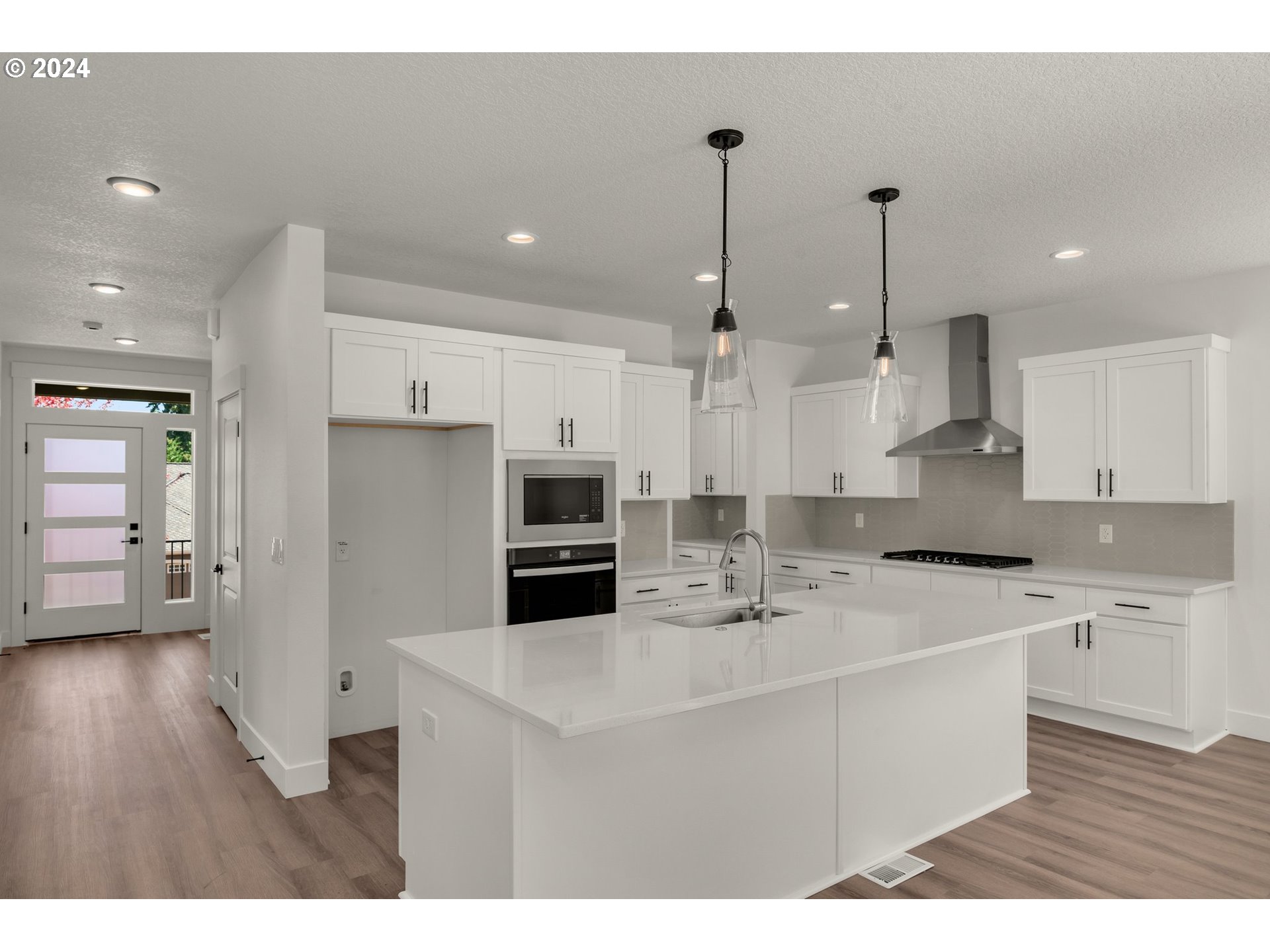 7939 Southwest 176th Terrace, Unit LOT1 Beaverton, OR 97007 - Photo 6 of 25 a kitchen with stainless steel appliances kitchen island granite countertop a refrigerator a sink a stove and white cabinets with wooden floor