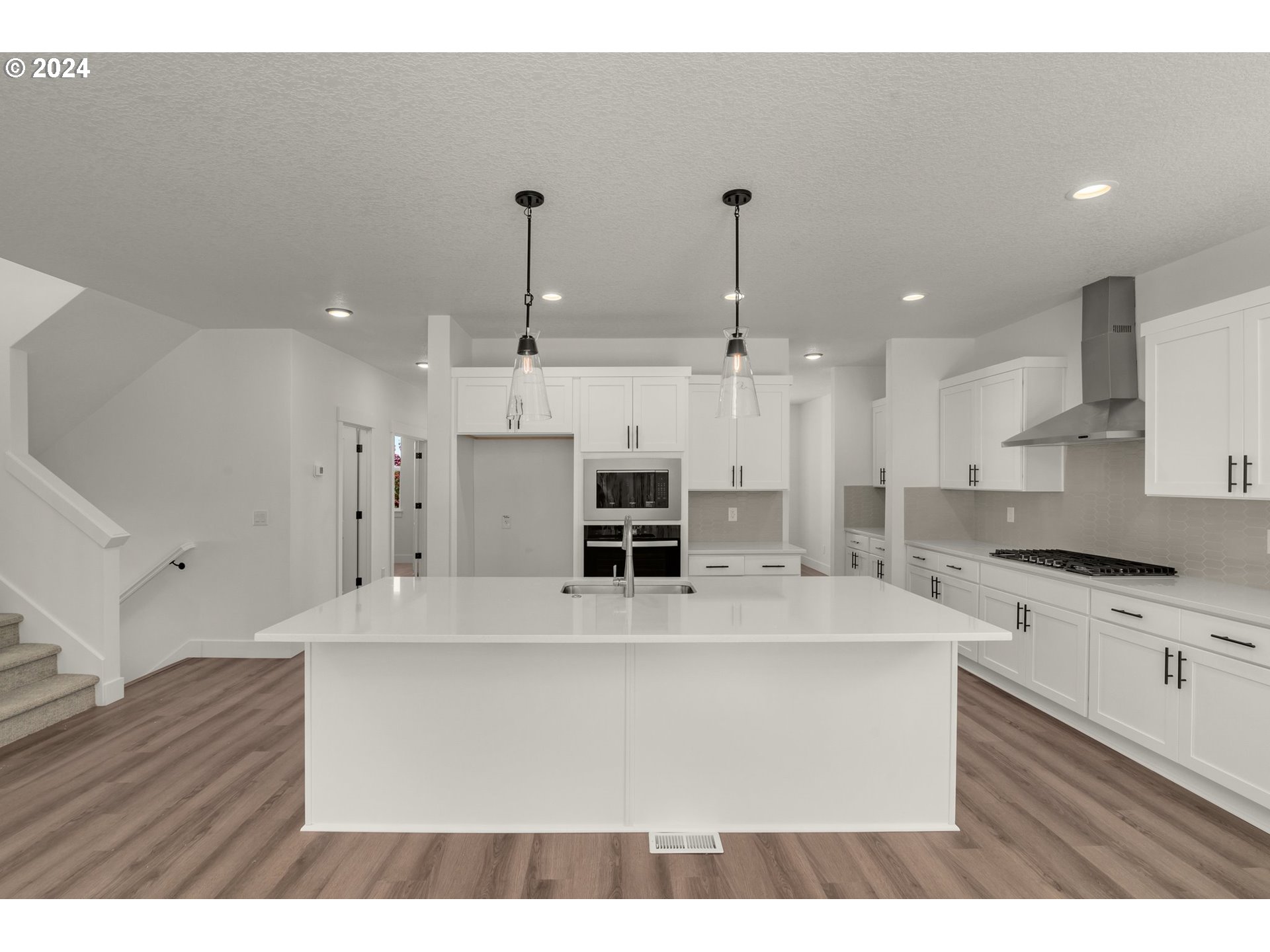 7939 Southwest 176th Terrace, Unit LOT1 Beaverton, OR 97007 - Photo 7 of 25 a large white kitchen with stainless steel appliances kitchen island granite countertop a stove a sink a refrigerator and white cabinets with wooden floor