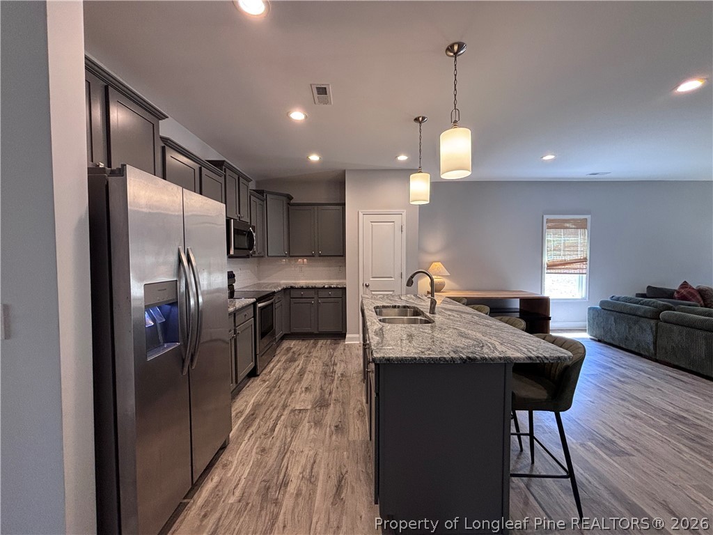 7720 Rufus Johnson Road Fayetteville, NC 28306 - Photo 16 of 50 a kitchen with stainless steel appliances granite countertop a refrigerator a sink dishwasher a stove and a dining table with wooden floor