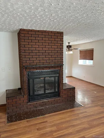 a view of an empty room with wooden floor and a fireplace