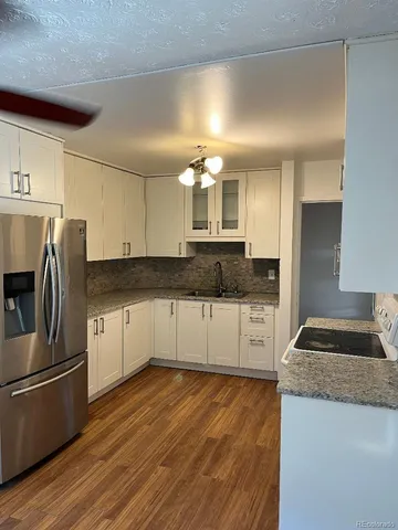 a kitchen with granite countertop a refrigerator and a stove top oven