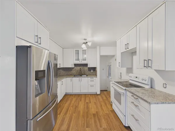 a kitchen with granite countertop a refrigerator stove top oven and sink