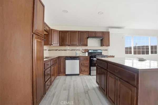 a kitchen with stainless steel appliances granite countertop a stove top oven a sink dishwasher and a refrigerator with wooden floor