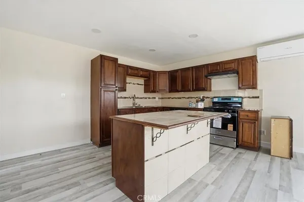 a kitchen with granite countertop wooden cabinets and a stove top oven