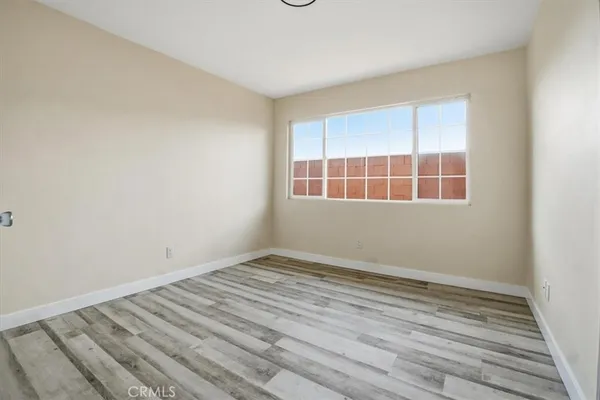 an empty room with wooden floor closet and windows