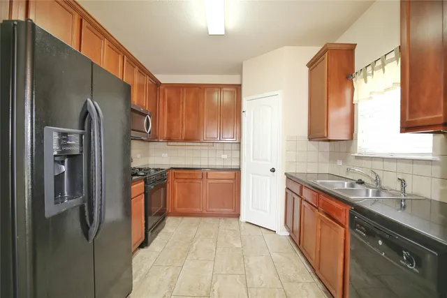 a kitchen with stainless steel appliances granite countertop a refrigerator a sink dishwasher a stove with wooden cabinets and floor