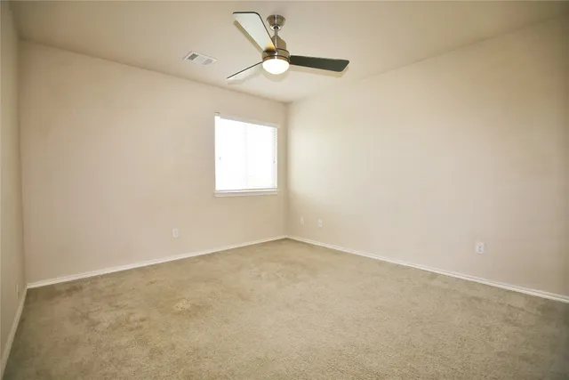an empty room with a window and a fan