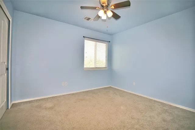 an empty room with a window and a fan