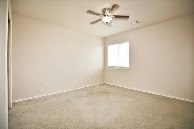 an empty room with a window and a fan
