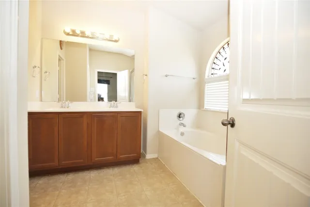 a bathroom with a bathtub a mirror a sink and vanity