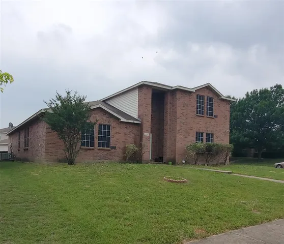 a house that is sitting in the grass with large trees