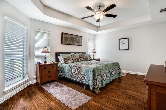 a bedroom with a bed and a dresser with wooden floor