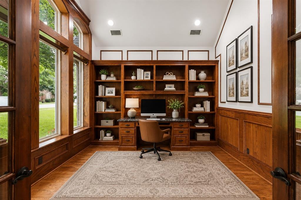 967 East Bethel School Road Coppell, TX 75019 - Photo 7 of 39 Dedicated office space featuring extensive built-in wooden shelving, a built-in desk with a stone countertop, rich wood-paneling, and large arched windows
