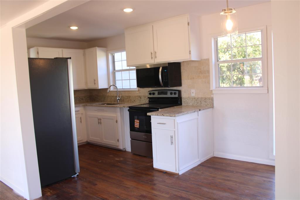 101 North 2 Nd Mullin, TX 76864 - Photo 21 of 34 a kitchen with kitchen island granite countertop a stove a sink and a refrigerator