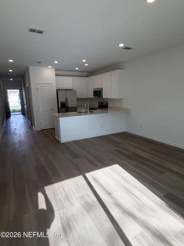 a view of kitchen with refrigerator stove and wooden floor