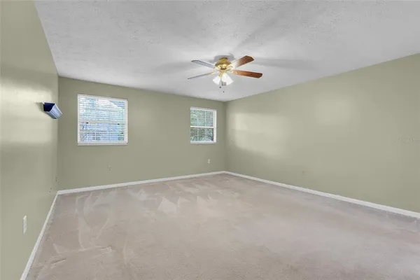 an empty room with windows and a chandelier fan
