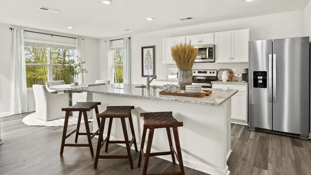 a kitchen with stainless steel appliances granite countertop dining table chairs refrigerator and microwave