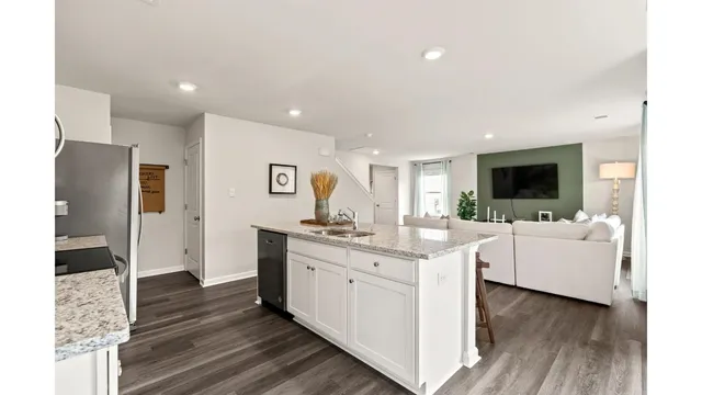 a large white kitchen with a stove top oven a sink and dishwasher with wooden floor