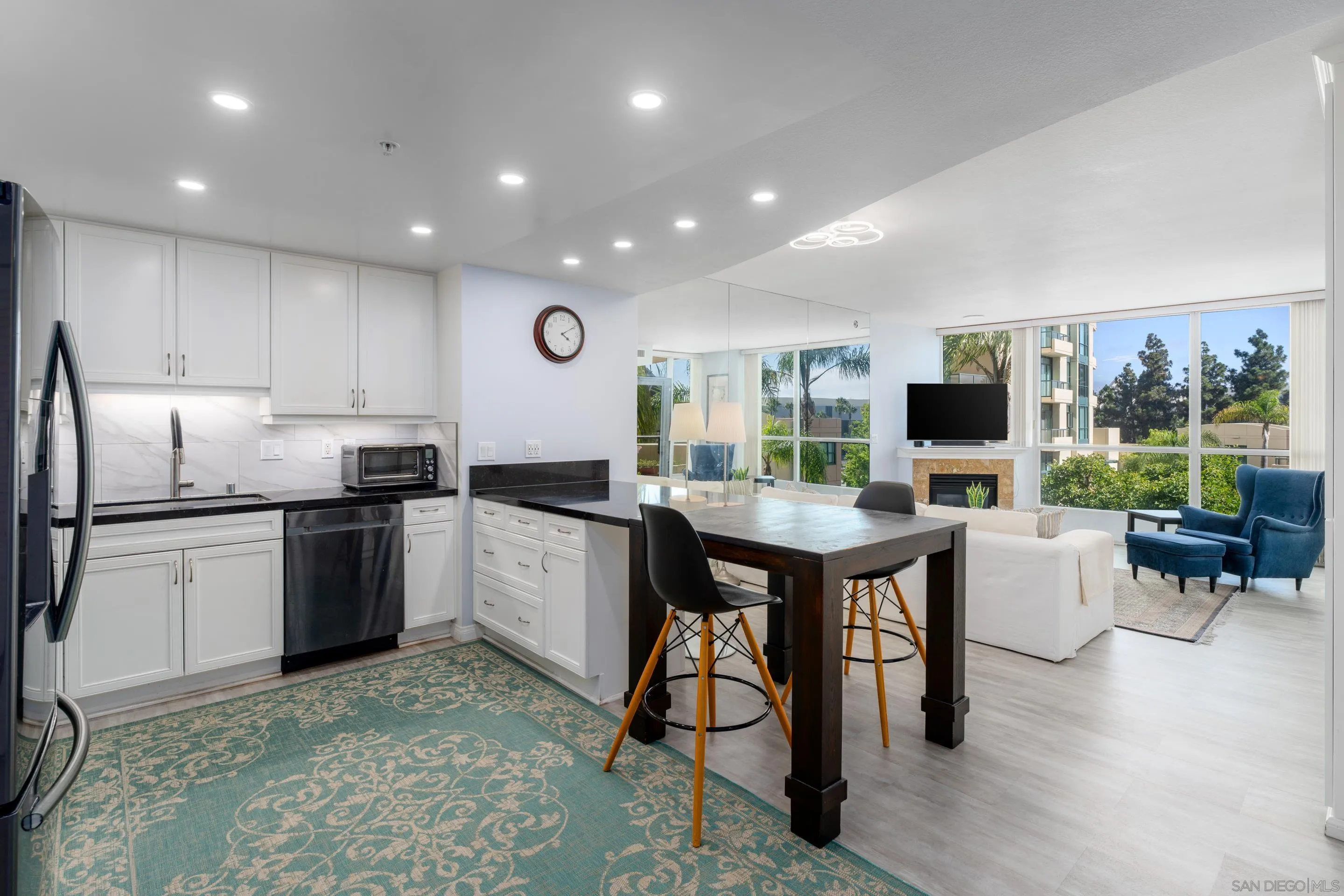 555 Front Street, Unit 303 San Diego, CA 92101 - Photo 2 of 35 a kitchen with stainless steel appliances granite countertop a stove a refrigerator a kitchen island a sink dishwasher and white cabinets with wooden floor