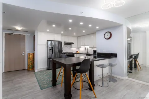 a kitchen with stainless steel appliances kitchen island granite countertop a refrigerator a stove a sink a dining table and chairs with wooden floor