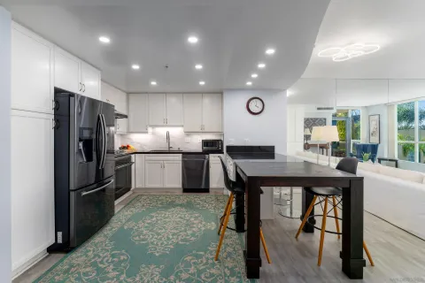 a kitchen with refrigerator a center island a stove and a dining table with wooden floor