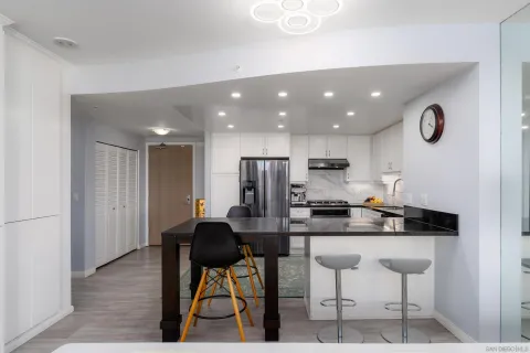 a kitchen with stainless steel appliances kitchen island granite countertop a table chairs and a refrigerator
