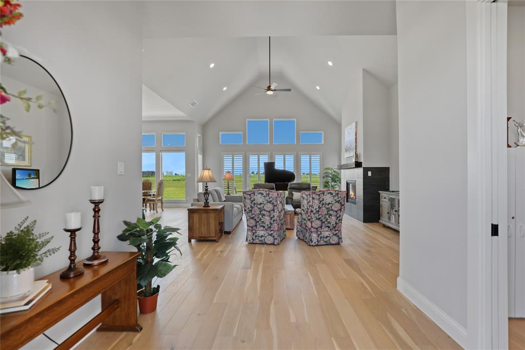 801 Lexington Lane Nevada, TX 75173 - Photo 6 of 40 Living room with high vaulted ceiling, a glass covered fireplace, light wood-style flooring, a ceiling fan, and recessed lighting