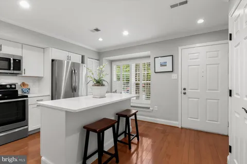 a kitchen with stainless steel appliances a dining table chairs refrigerator and sink