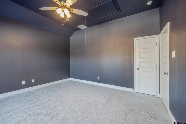 a view of an empty room with window and chandelier fan