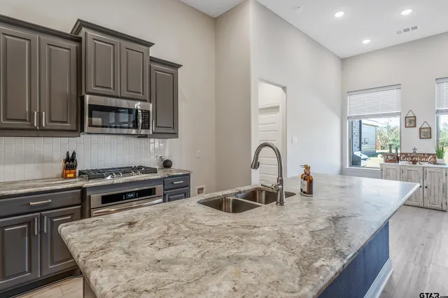 a kitchen with stainless steel appliances granite countertop a stove a sink and a microwave