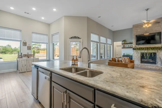 a kitchen with stainless steel appliances granite countertop a sink a stove and a wooden floors