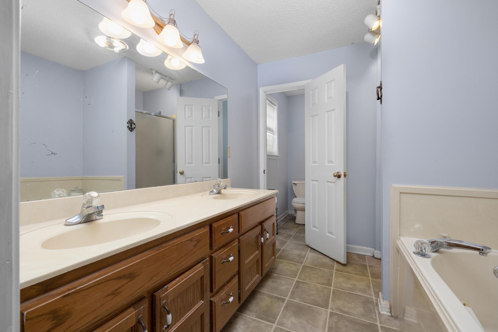 275 Morris Road Covington, TN 38019 - Photo 20 of 32 Full bathroom featuring tile patterned flooring, a textured ceiling, toilet, vanity, and independent shower and bath